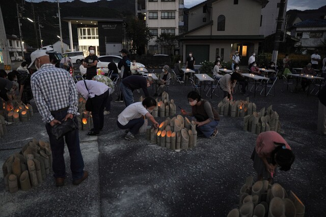 竹灯籠に火を点ける人々